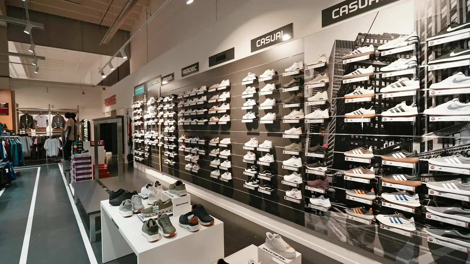 Lange sneakerwand in de winkel, met bordjes voor indoor-, aerobic- en casualschoenen
