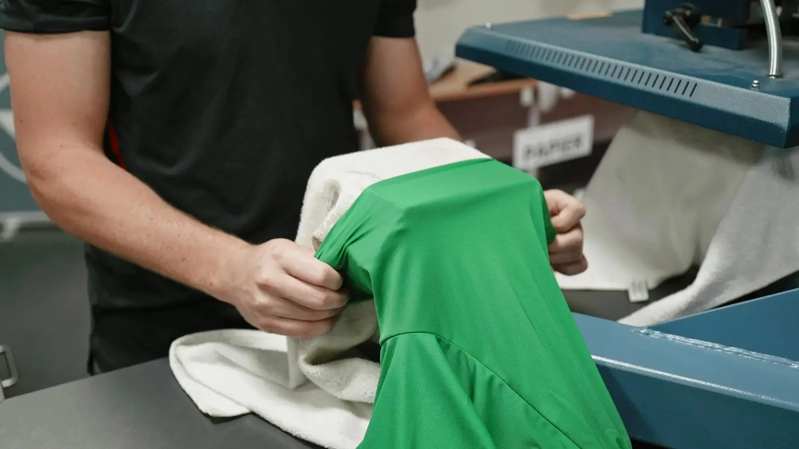 Medewerker trekt een groen shirt over de arm van de transferpers