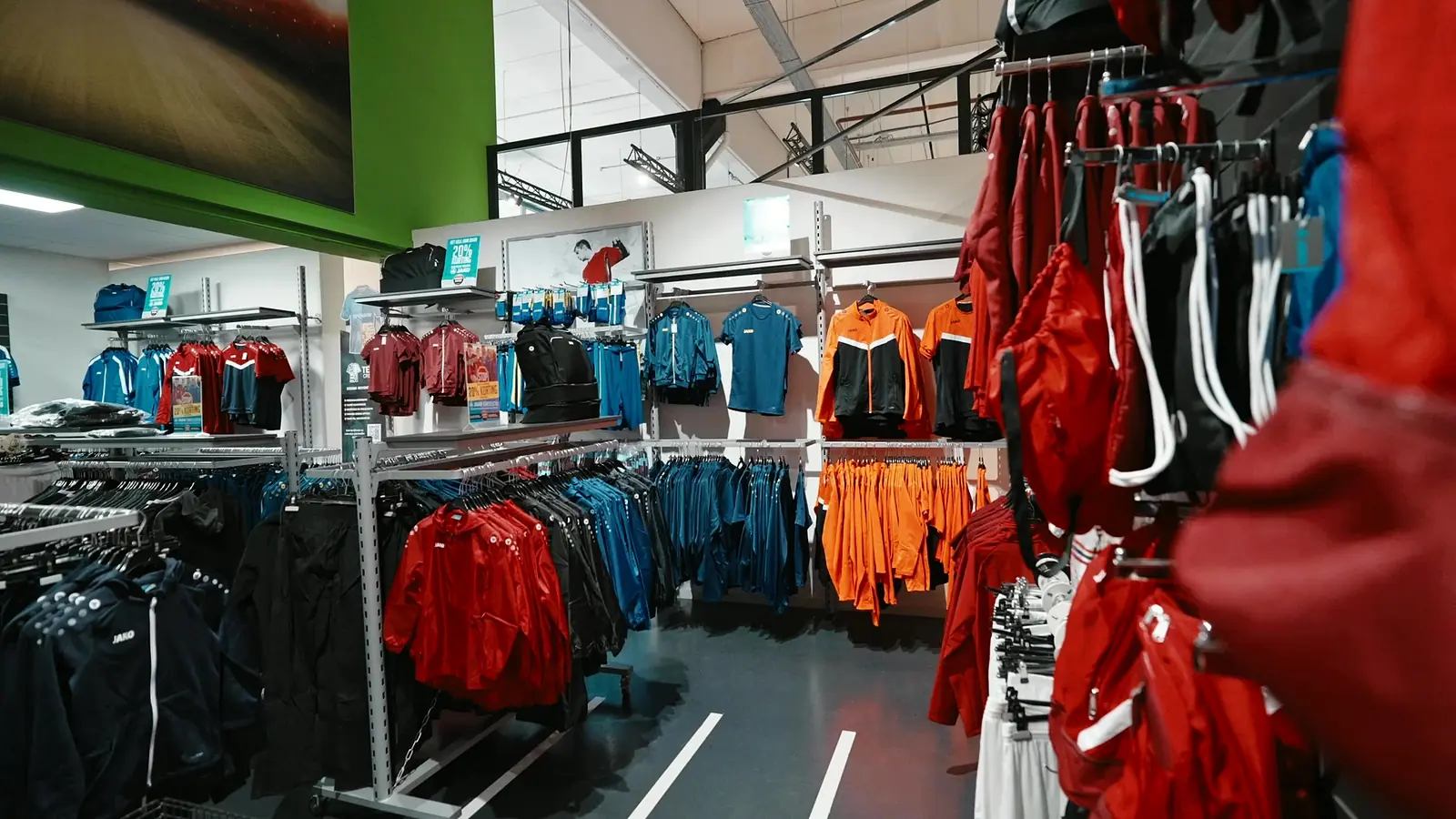 Rekken met JAKO-teamkleding in rood, blauw en oranje op de teamsportafdeling