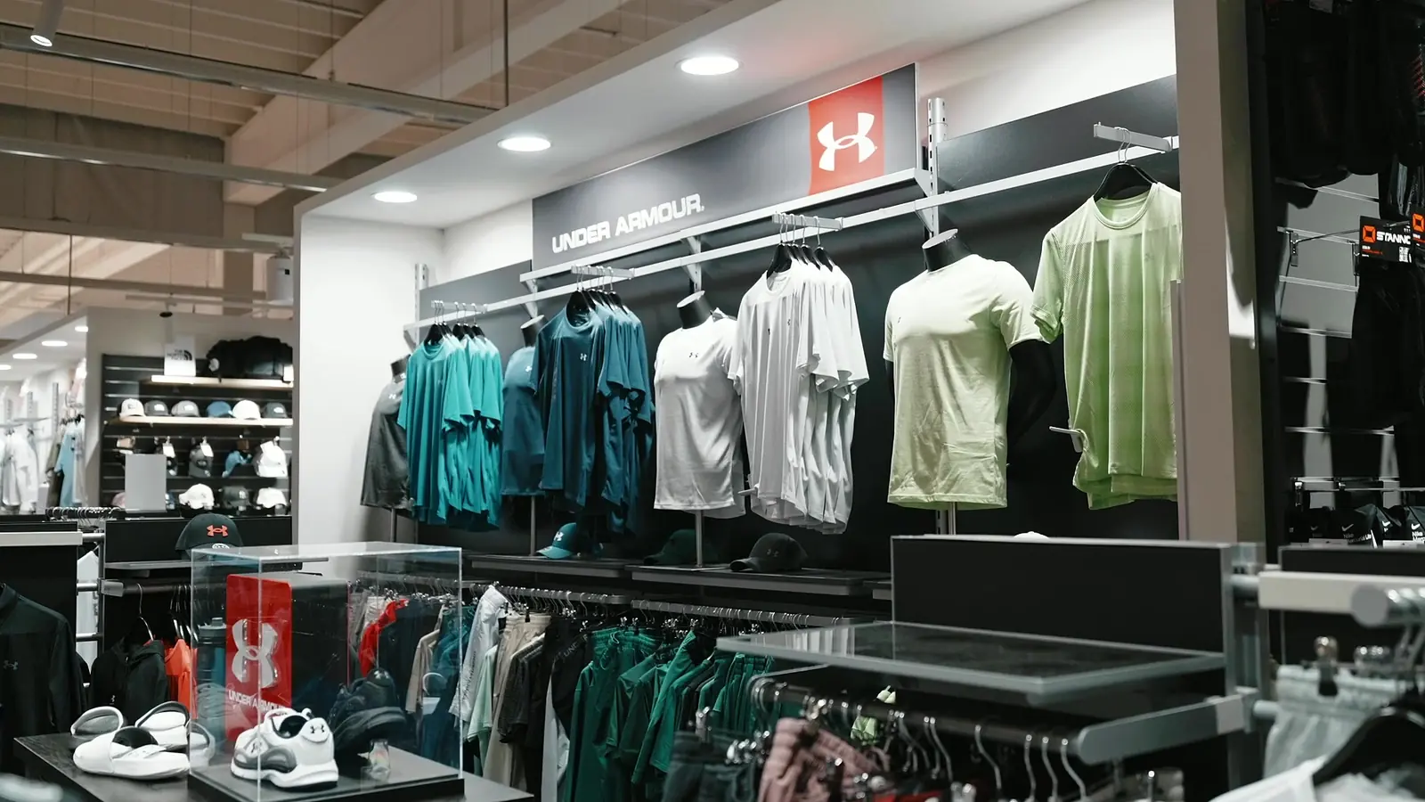 Under Armour shop-in-shop met sportshirts aan een rail onder het merklogo