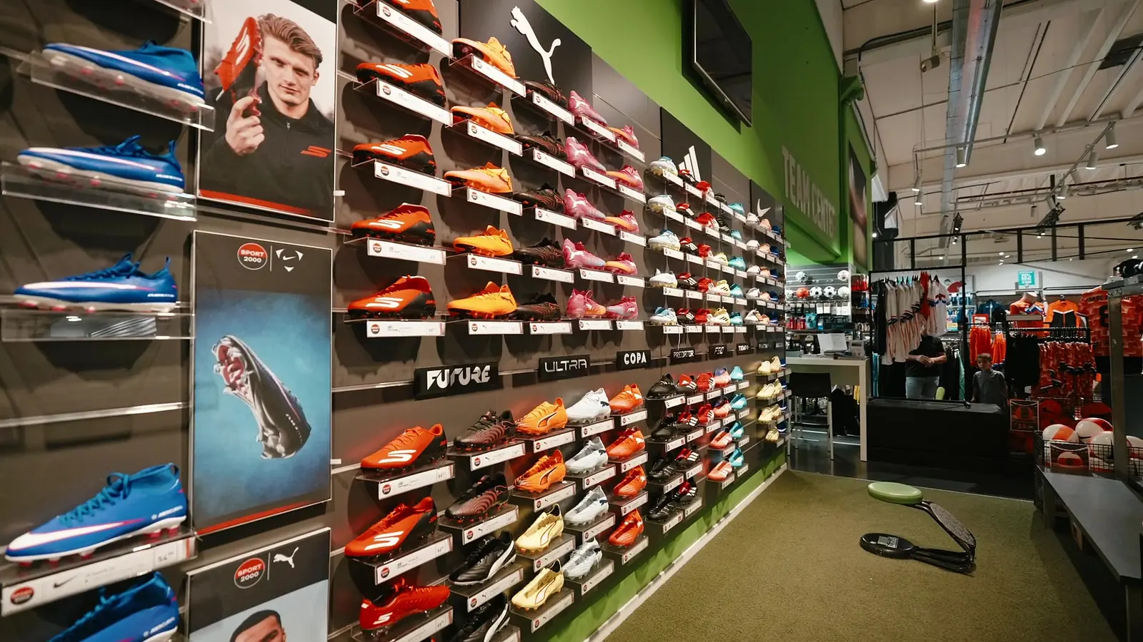 De voetbalschoenenwand met schoenen van Puma, adidas en Nike op verlichte schappen